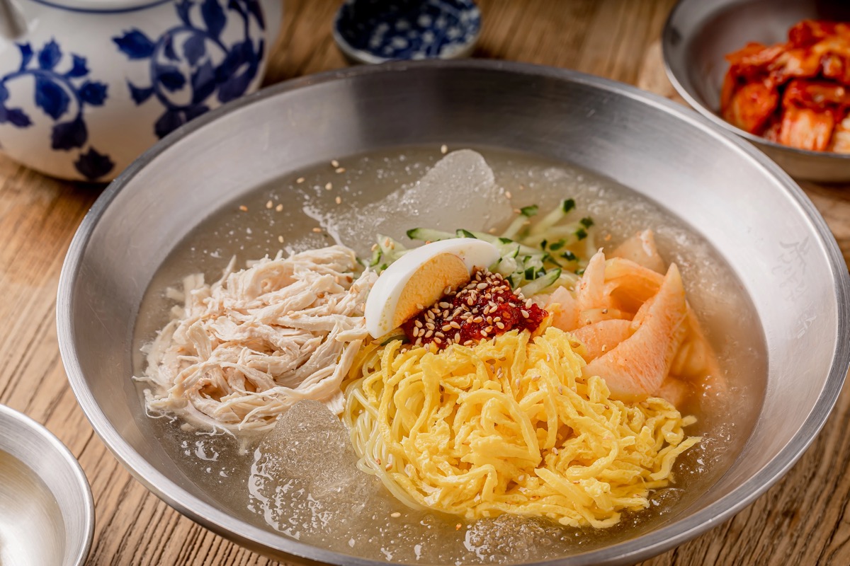 Eonyang chicken noodle soup with handmade noodles, kimchi and pickled radish
